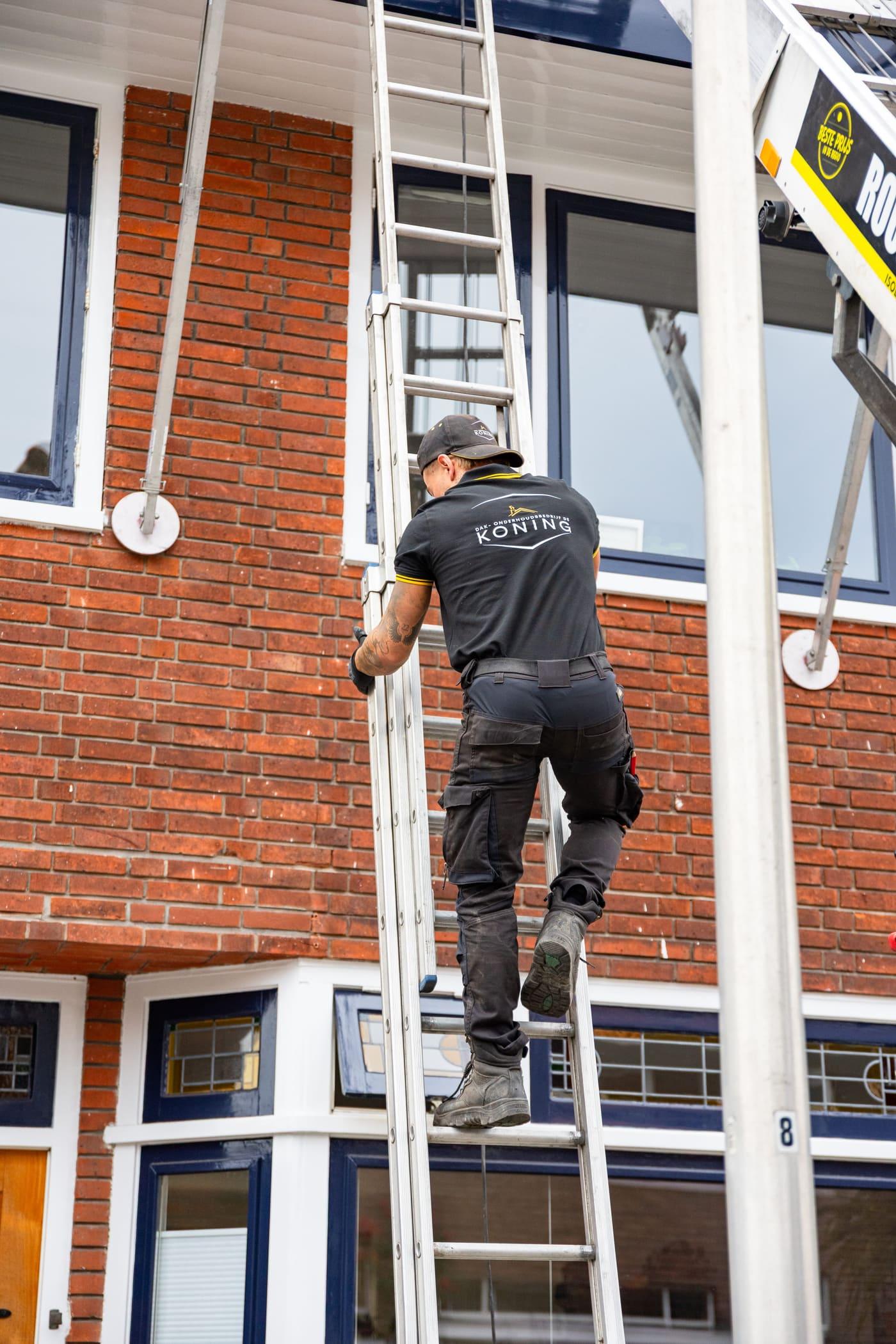 Vakman van De Koning beklimt de ladder tijdens werk op locatie